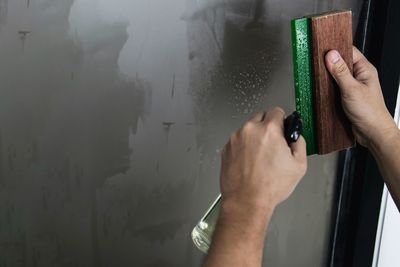 Midsection of person holding paper against wall