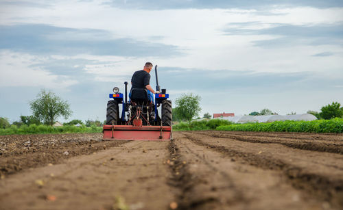A farmer drives a tractor and cultivates an agricultural field. milling soil, cutting rows.