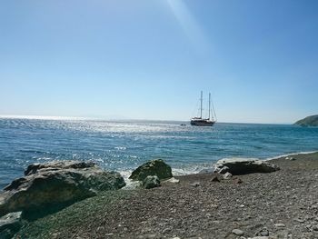 View of boats in calm blue sea against clear sky