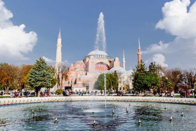 View of fountain in pond against buildings