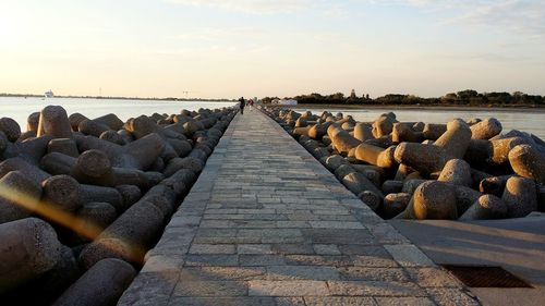 Rocks by sea against sky during sunset