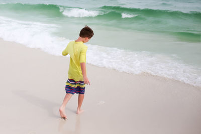 Rear view of boy walking at beach