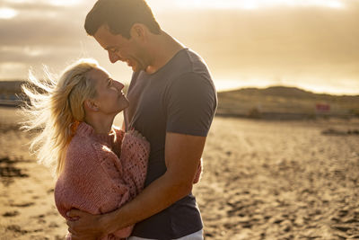 Side view of couple embracing at beach