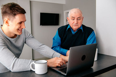 Grandfather with grandson using laptop at home