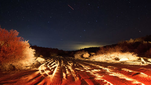 Scenic view of illuminated land against sky at night