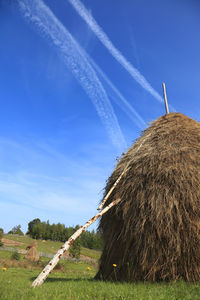 Hay bales on field against blue sky