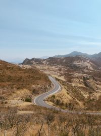 Scenic view of road by mountains against sky