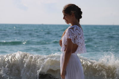 Woman standing at beach against sky