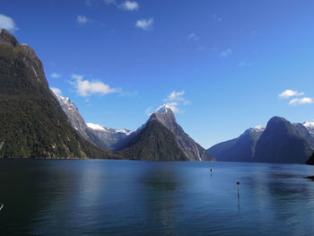 Scenic view of lake and mountains against blue sky