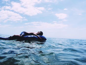 Man relaxing in sea against sky