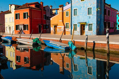 Boats moored on canal by buildings in city