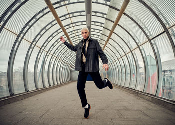 Full length portrait of man with arms raised in tunnel