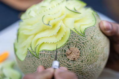 Cropped hands carving cantaloupe