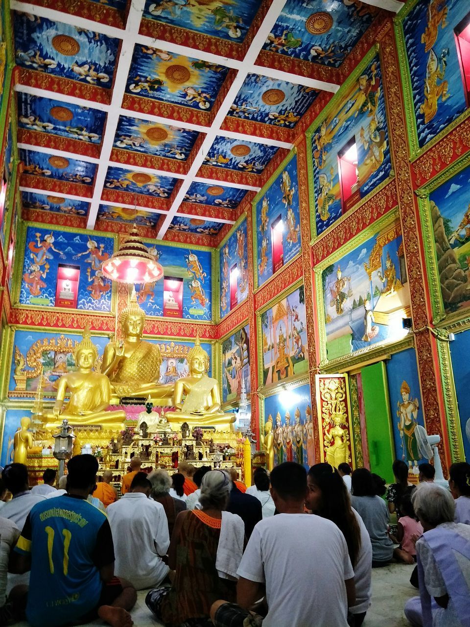 REAR VIEW OF PEOPLE IN ILLUMINATED TEMPLE