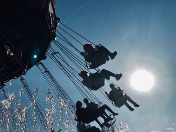 Low angle view of people enjoying chain swing ride at amusement park against sky