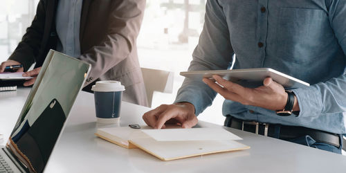 Midsection of man using mobile phone on table