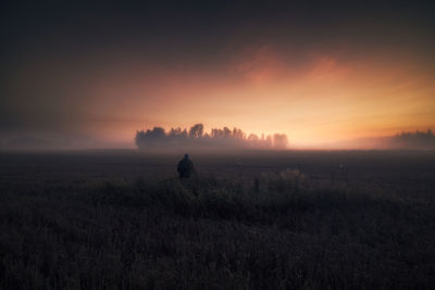 Man standing on field against sky during sunset