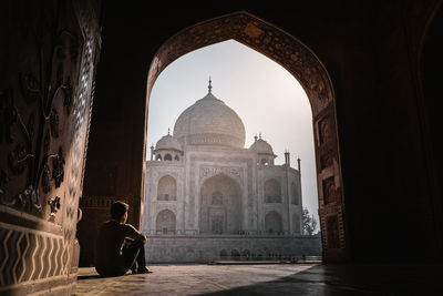 Man looking at taj mahal through arch