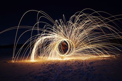 Illuminated wire wool spinning against sky at night