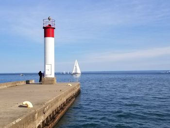 Lighthouse by sea against sky