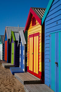 Multi colored houses on beach against clear blue sky