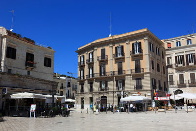 People in front of buildings against clear blue sky