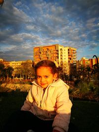 Portrait of young woman against sky in city