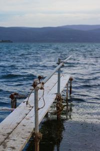 Close-up of railing by sea against sky