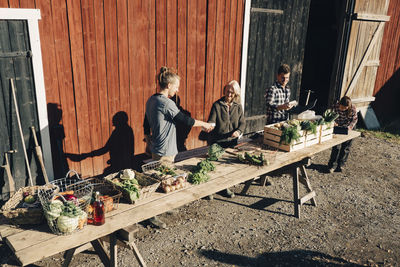 Multi-ethnic farmers selling organic vegetables outside barn