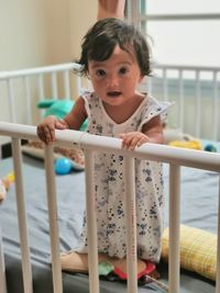 Portrait of cute baby girl staying on railing