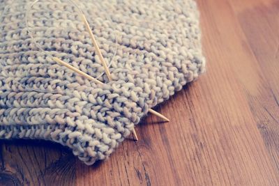 Knitting needles with scarf on wooden table