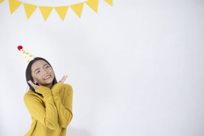 Smiling girl standing against yellow wall