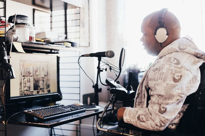 Side view of disabled man wearing headphones while looking at computer