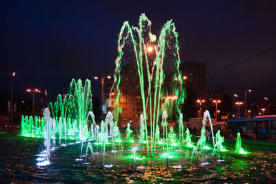 Illuminated fountain in city against sky at night