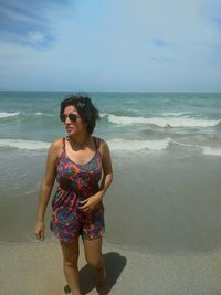 Beautiful young woman on beach against sky