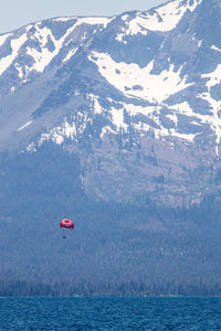 Scenic view of a lake  by snowcapped mountain and a paraglider