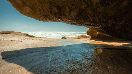 Rock formation on beach against sky