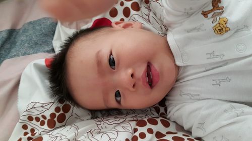 High angle portrait of cute baby boy lying on bed at home