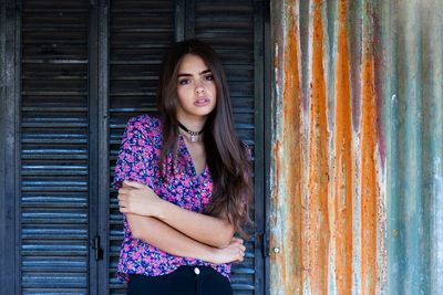 Portrait of beautiful young woman standing against wall