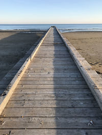 Boardwalk leading towards sea against sky