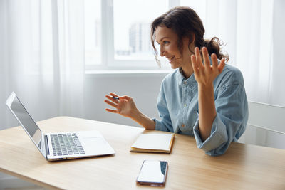 Young woman using mobile phone while sitting on table