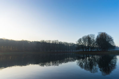 Reflection of trees in lake against clear sky