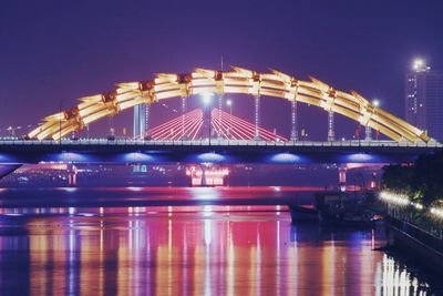 Illuminated bridge over river at night