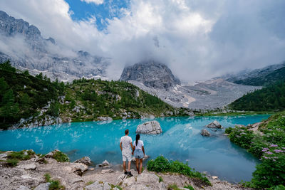 Rear view of people standing by lake against sky