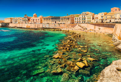 Buildings by sea against sky