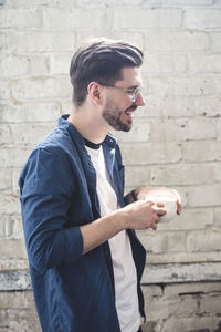 Side view of young man standing against wall