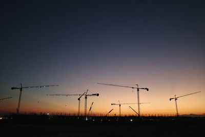 Low angle view of electricity pylon against sky during sunset