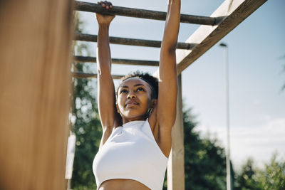 Female athlete hanging on monkey bar in park