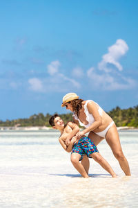 Rear view of young woman sitting on beach