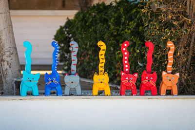 Multicolored wooden cat souvenirs stand in a row for sale in a store